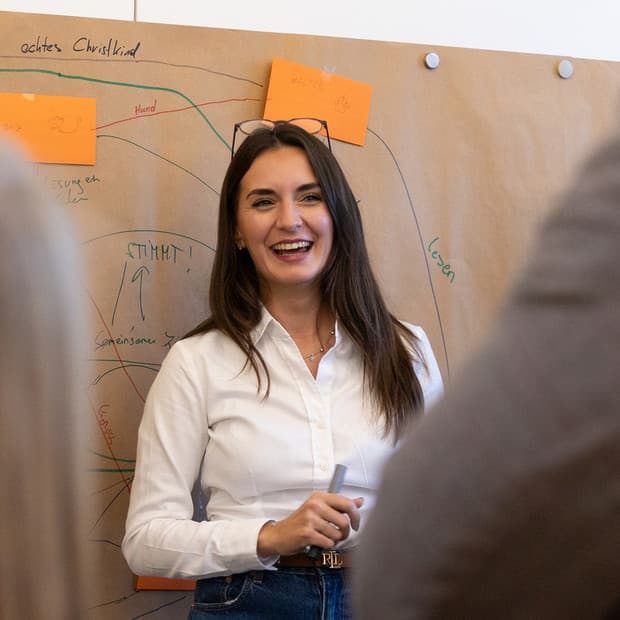 Matea steht mit einem sympathischen Lächeln vor einem Publikum und erzählt von Leadership, Changemanagment & HR.